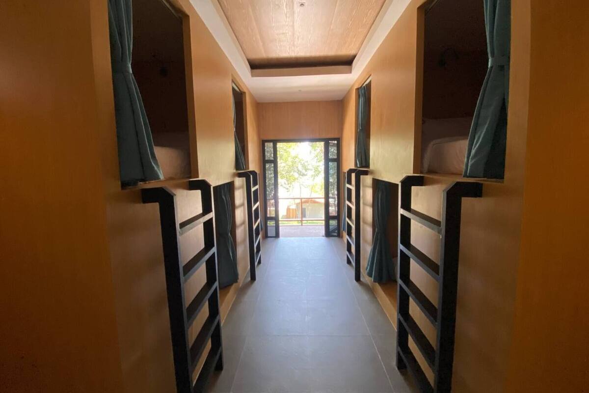 A corridor with bunk beds, wooden walls, and a tiled floor.