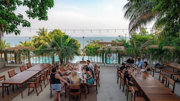 Enjoy a scenic ocean view from our outdoor dining area, surrounded by lush greenery and perfect for social gatherings.