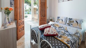 A bedroom with a bed, wooden door, and a view of the outdoors.
