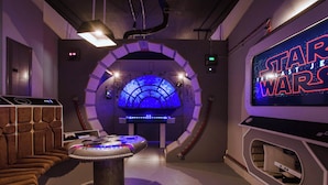 A Star Wars-themed room with a gaming console, a futuristic seating area, and a large screen displaying the movie title. - Chic Home, Themed Bedrooms, Game Room, Best Spot (Kissimmee)