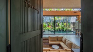 A modern living room with a large window, a sofa, and a coffee table. - The Mystik Loft Harmony (Canggu)