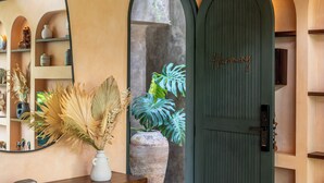 A reception area with a green door, a large mirror, and a plant in a vase. - The Mystik Loft Harmony (Canggu)