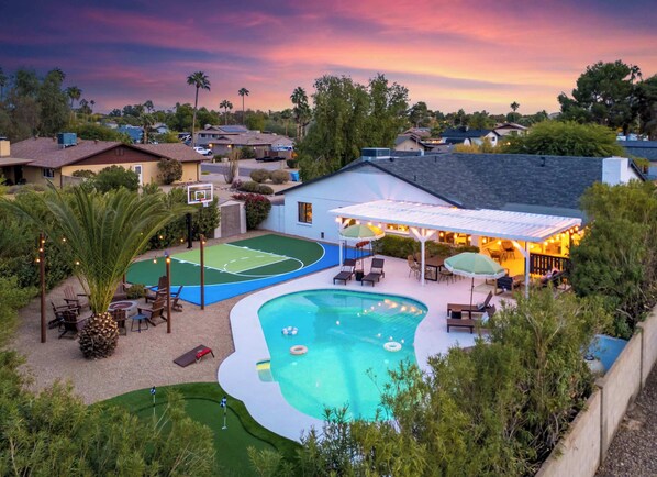 A residential backyard with a swimming pool, a basketball court, and outdoor seating. - Epic Desert Stay | Pool, Hot Tub & Sports Court (Scottsdale)