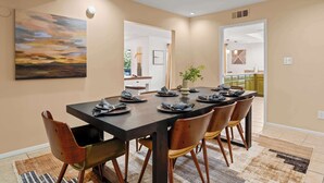 Un coin repas avec une table en bois foncé, dressée pour six personnes, entourée de chaises en bois.