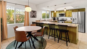 Une cuisine moderne dotée d’un îlot central, de tabourets de bar et d’une table à manger avec des chaises.