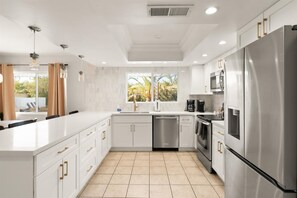 Modern kitchen with stainless steel appliances and a large white countertop.