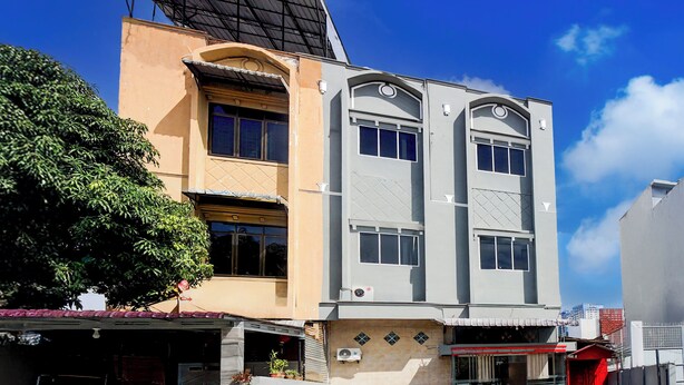 A multi-story building with a mix of architectural styles, including a flat roof and a curved facade. - Hotel O Medan City Center Near Plaza Medan Fair Formerly Waringin Residence (Medan)