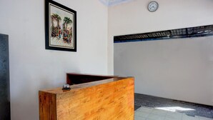 A reception desk with a wooden finish, a framed painting above it, and a clock on the wall. - Hotel O Medan City Center Near Plaza Medan Fair Formerly Waringin Residence (Medan)