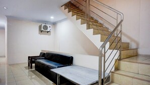 A staircase with metal railings leading to a landing. A black leather sofa and a small table are positioned on the landing. - Hotel O Medan City Center Near Plaza Medan Fair Formerly Waringin Residence (Medan)