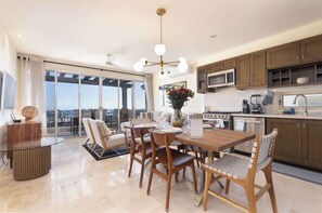 Uma cozinha moderna com armários de madeira, uma área de refeições com mesa de vidro e vista para a cidade.