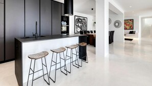 Une cuisine moderne dotée d’un îlot central, de tabourets de bar et d’un coin repas avec une table et des chaises en bois.