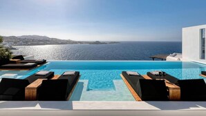 A modern infinity pool with lounge chairs and a view of the sea. - Villa With Fantastic Terrace-sea Views (Mykonos)