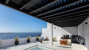Une terrasse sur le toit avec un jacuzzi, un espace salon et une vue sur la mer.
