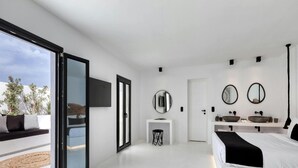 A modern bedroom with a large sliding glass door leading to a balcony, a central white bedside table, a double bed, and a built-in sink with two mirrors. - Villa With Fantastic Terrace-sea Views (Mykonos)