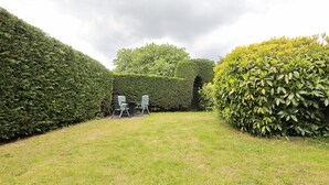 A neatly trimmed lawn with a small seating area and a hedge. - Seagull Bungalow Park Sollasi (Noordwijkerhout)
