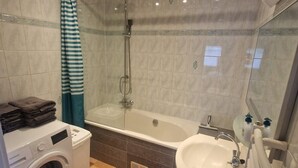 A bathroom with a washing machine, a bathtub, a sink, and a shower. - Seagull Bungalow Park Sollasi (Noordwijkerhout)