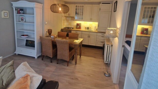 A compact living space with a dining area, kitchenette, and a bookshelf. - Seagull Bungalow Park Sollasi (Noordwijkerhout)