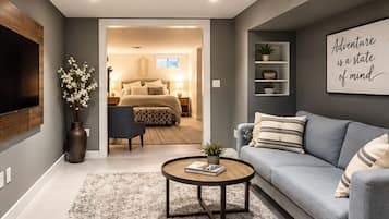Uma sala de estar moderna com sofá, mesa de centro e televisão. Há um corredor que leva a um quarto com cama e porta.