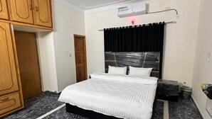 A bedroom with a bed, a ceiling fan, a wardrobe, and a radiator. - Taj Villa (Islamabad)