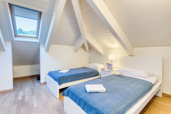 A bedroom with two beds, a skylight, and a wooden floor. - Il Regno Di Monica Attico Near The Sea (Alassio)