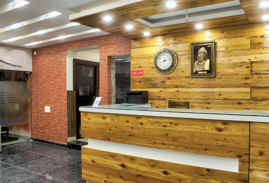 A reception desk with a wooden panel design, a clock, and a framed statue.