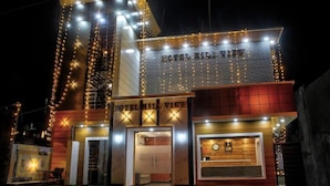 A hotel with a modern design, featuring a prominent entrance with a sign, a visible reception area, and a clock on the facade. - Hotel Hill View (Dehradun)