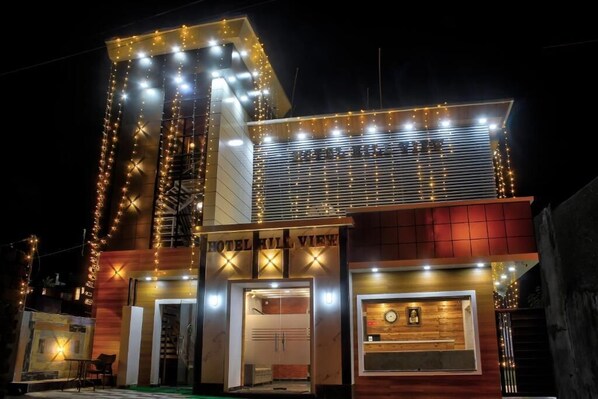 A hotel with a modern design, featuring a prominent entrance with a sign, a visible reception area, and a clock on the facade.