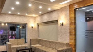 A modern lobby with a sofa, a coffee table, and a glass partition. - Hotel Hill View (Dehradun)