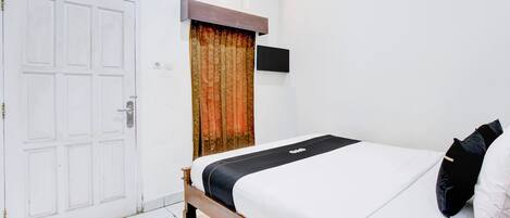 Un dormitorio con cama de madera, ropa de cama blanca, una cortina, un televisor montado y una puerta blanca.