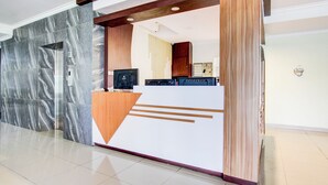 A reception area with a marble wall, a reception desk with a geometric design, and a wooden column.