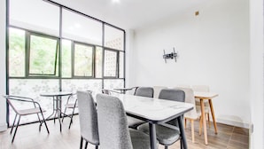 A modern meeting room with a large table and chairs, large windows with a view, and a mounted TV.