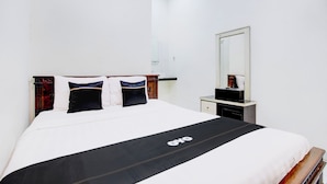 A hotel room with a large bed, a bedside table, a mirror, and a wardrobe.