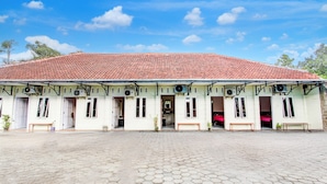 A building with a tiled roof, multiple doors, and a paved courtyard.