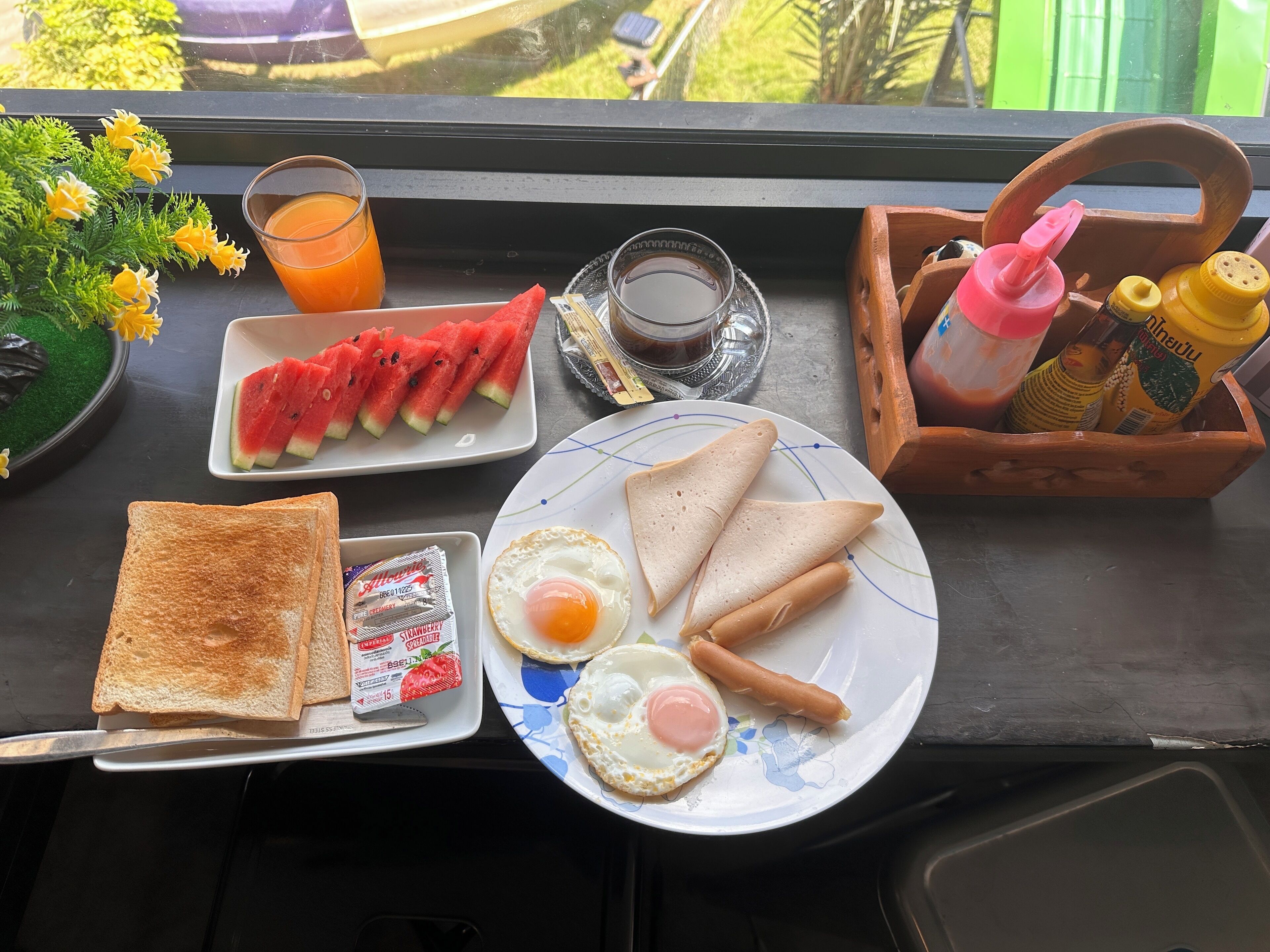 A breakfast tray with toast, eggs, and watermelon slices on a table by a window.