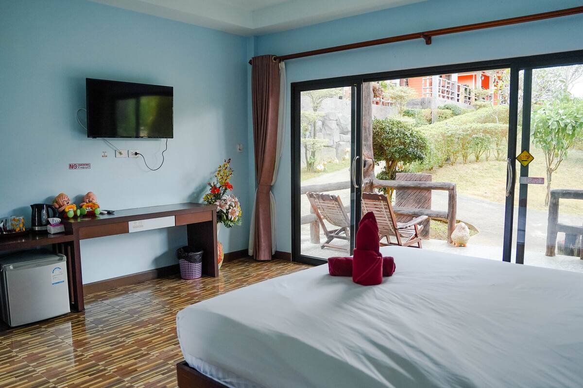 Une chambre d’hôtel comprenant un lit, un bureau avec une télévision, un petit réfrigérateur, une poubelle et une vue sur l’espace extérieur.
