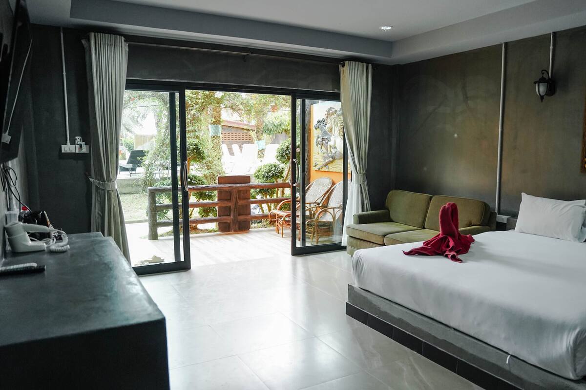 Une chambre d’hôtel moderne dotée d’un grand lit, d’un canapé et d’un balcon aménagé avec du mobilier d’extérieur.