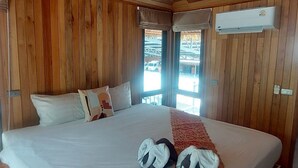 Una stanza con rivestimento in legno, un letto grande, un lampadario e una finestra con vista all'esterno.
