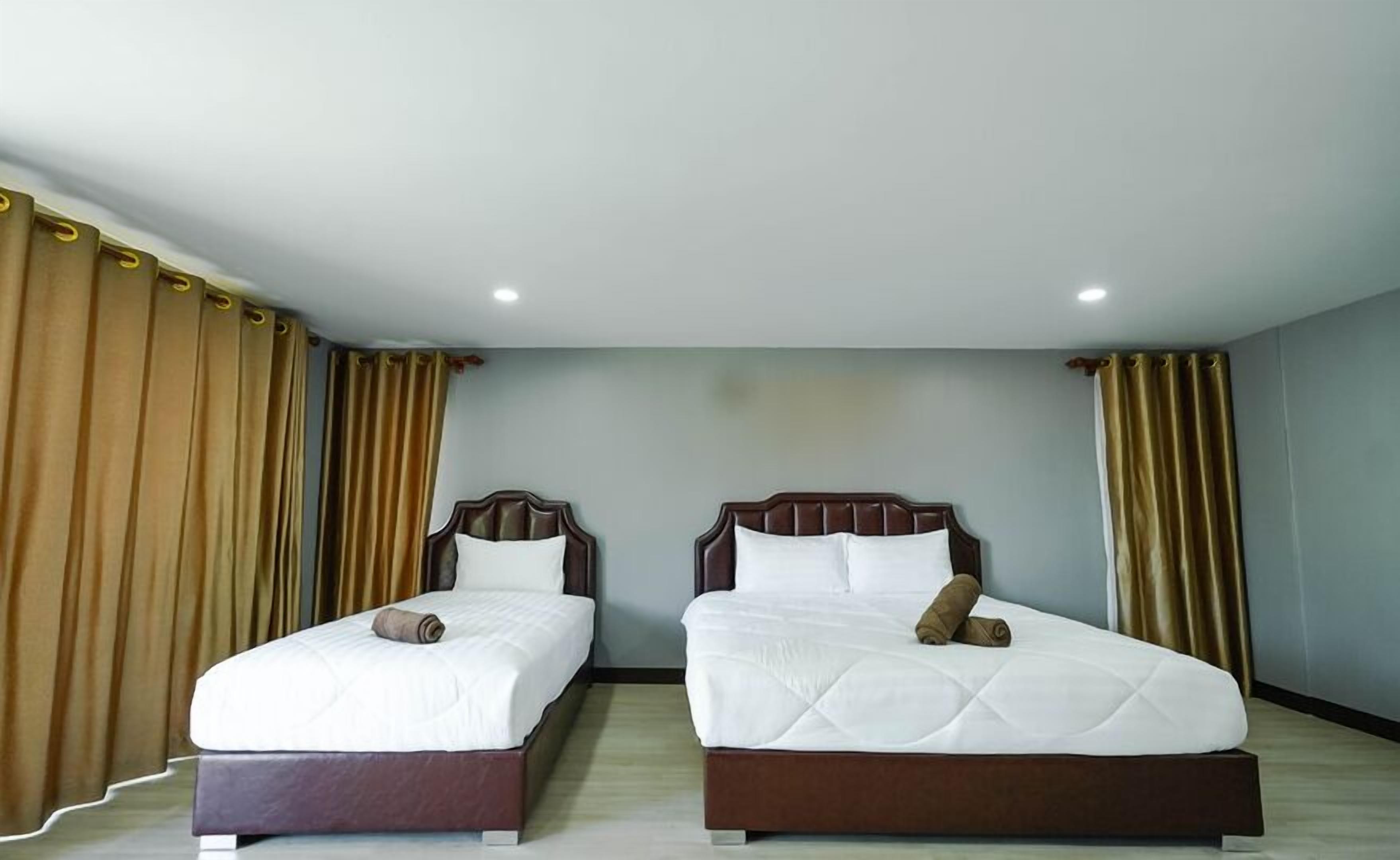 A hotel room with two beds, each with a wooden headboard and white bedding.