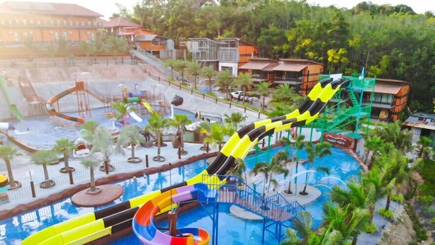 Un parco acquatico con diverse scivoli e una zona piscina circondata da palme e edifici.
