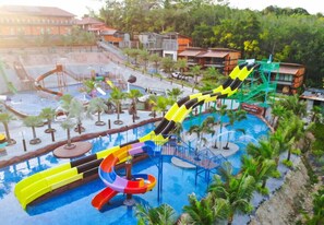 Un parc aquatique doté de nombreux toboggans et d’un espace piscine entouré de palmiers et de bâtiments.