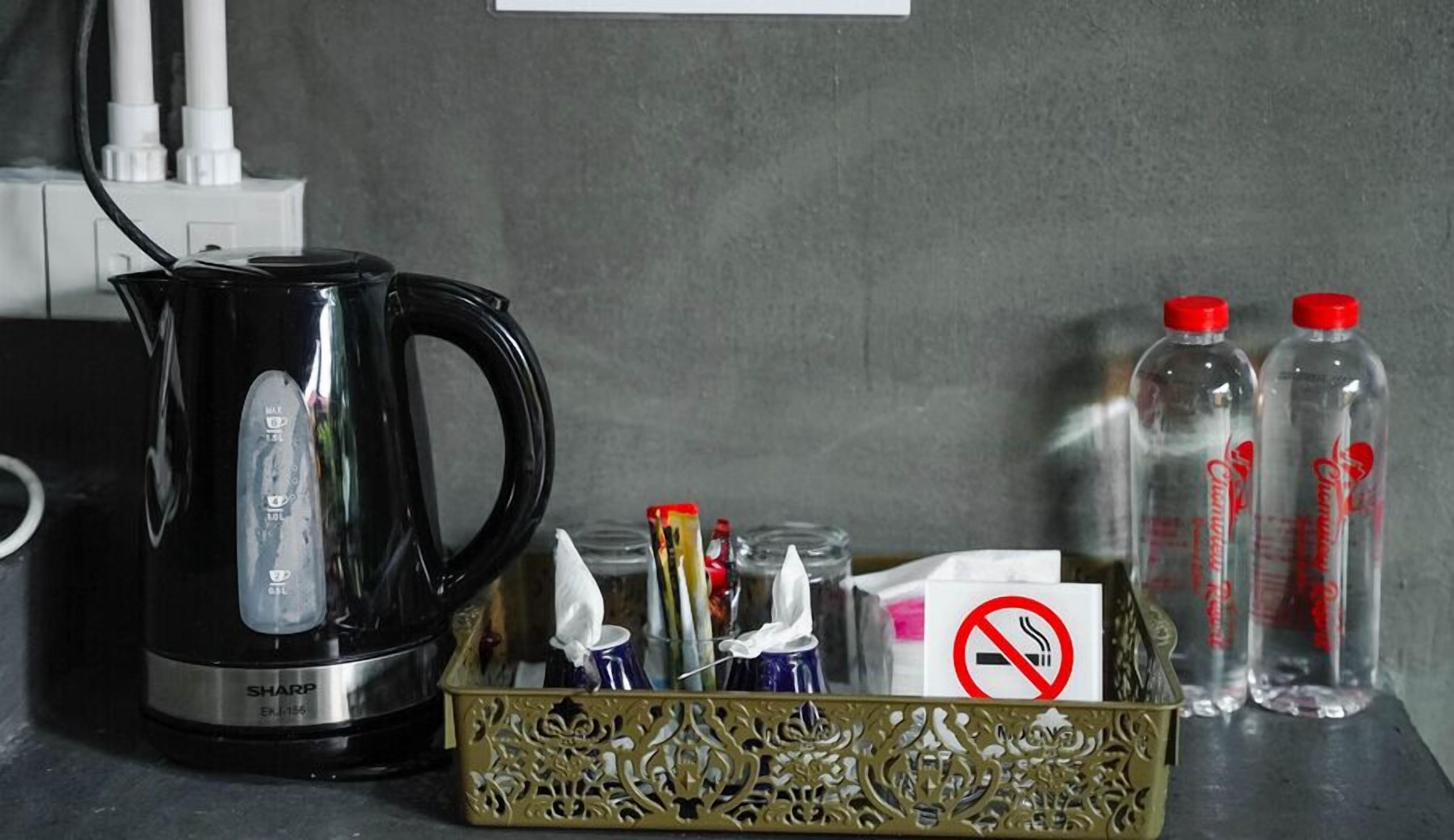 A black electric kettle, a decorative tray with items, and two bottles of water on a table.