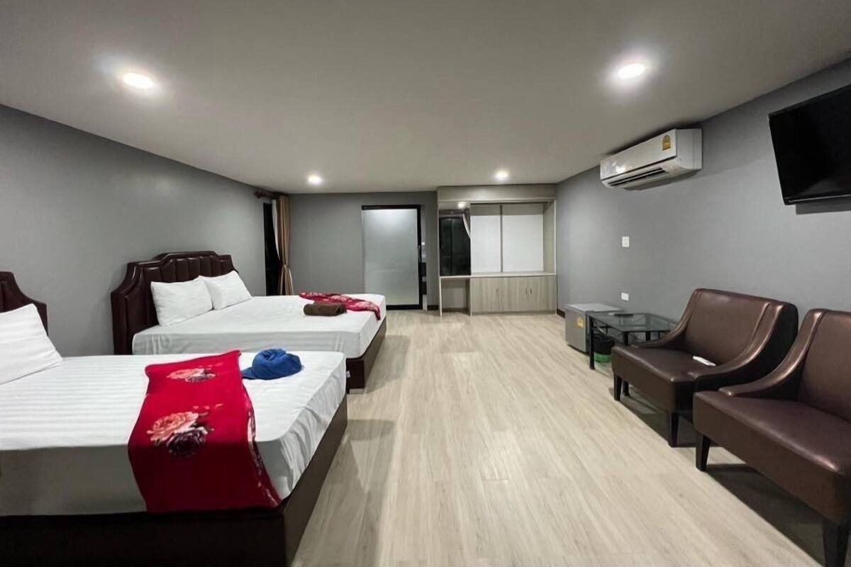 Une chambre d’hôtel avec deux lits, un canapé, une télévision et un appareil de climatisation.