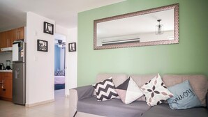 Sala de estar com sofá, cozinha e parede espelhada.