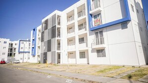 Um edifício residencial moderno de vários andares com varandas, uma placa visível com a inscrição 