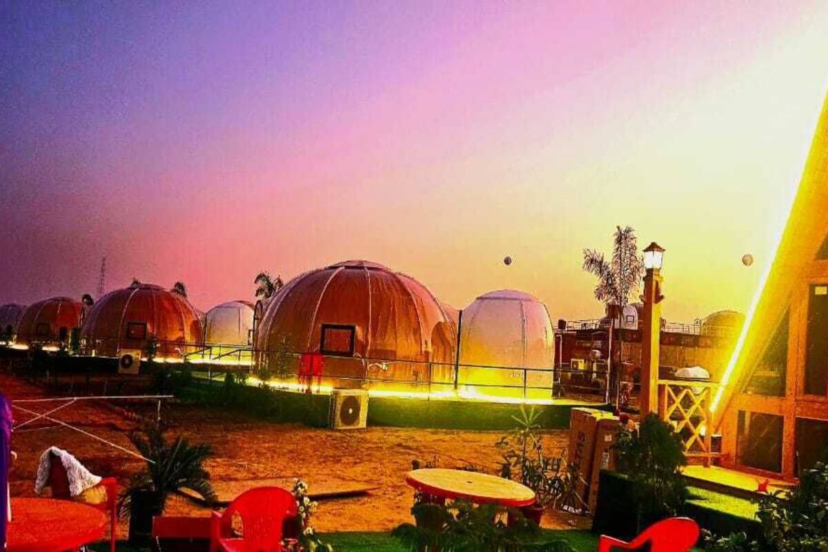 A series of dome-shaped accommodations with a central building featuring a sloped roof and illuminated edges.