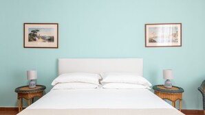 A neatly made bed with white linens in a room with light blue walls. There are two framed pictures on the wall, one on each side of the bed. - Charming bedroom in Sorrento with balcony (Sorrento)