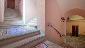 A staircase with patterned tiles leading to a door, a wall-mounted light fixture, and an archway. - Charming bedroom in Sorrento with balcony (Sorrento)