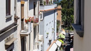 A narrow street with buildings featuring balconies with flower pots and outdoor seating. - Charming bedroom in Sorrento with balcony (Sorrento)