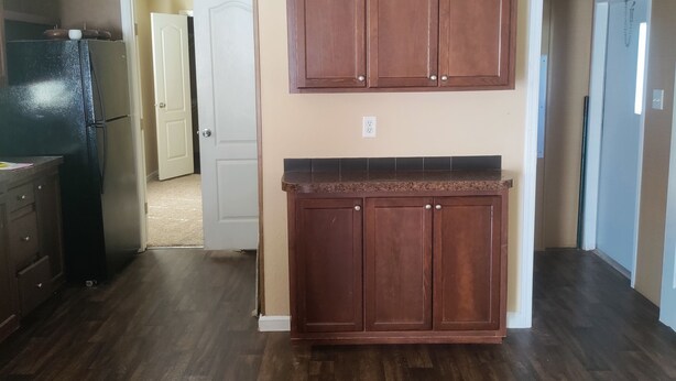 A kitchen with wooden cabinets, a refrigerator, and a countertop. - Reserve your very clean,quiet 3/2 mobile home in West San Antonio w/AC, WiFi (San Antonio)