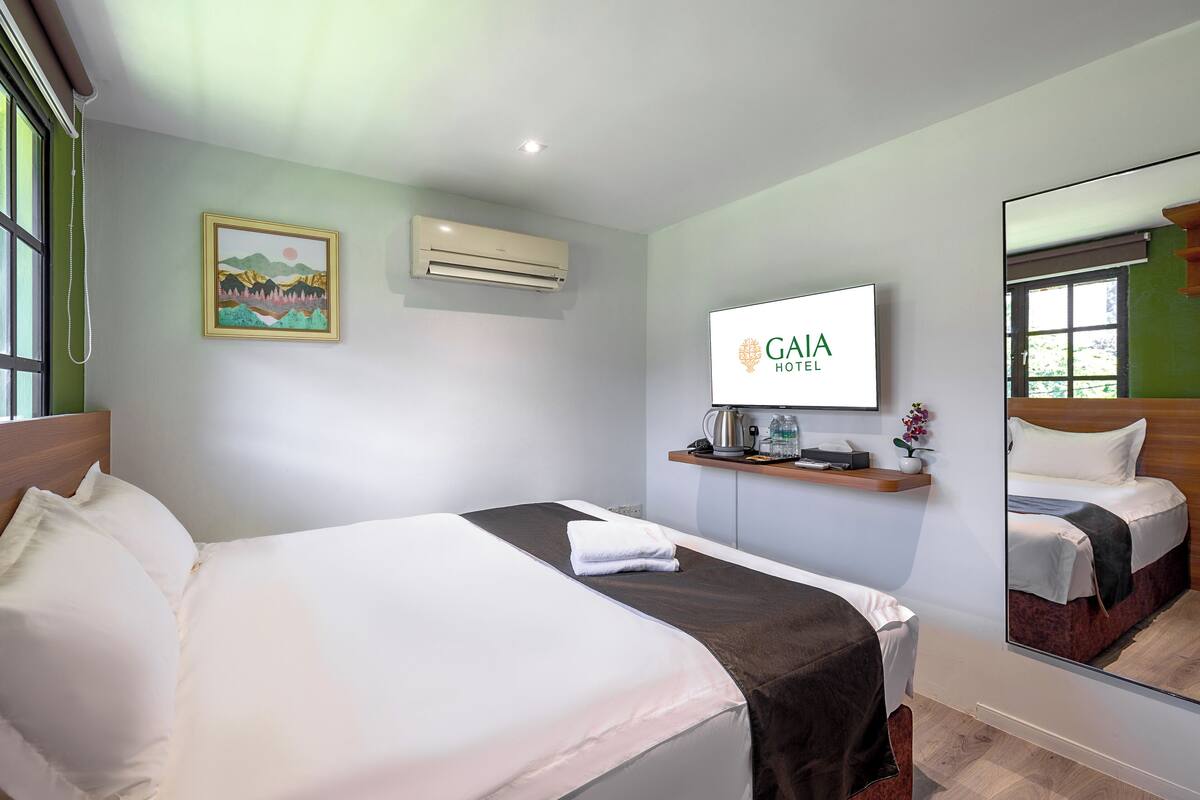 A hotel room with a bed, a mounted TV, a coffee maker, and a framed picture on the wall.